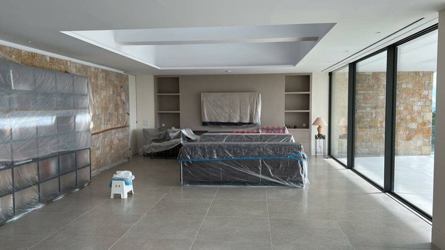 Salón de vivienda en fase de acabados, con revestimiento de piedra y grandes ventanales