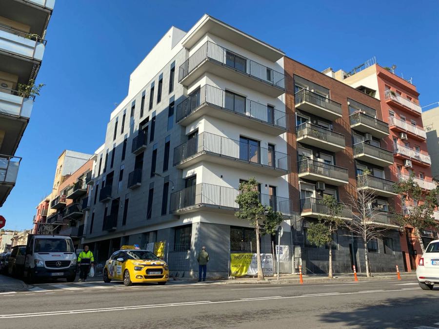 Edificio de viviendas en construcción en una calle, con vehículos de obra delante