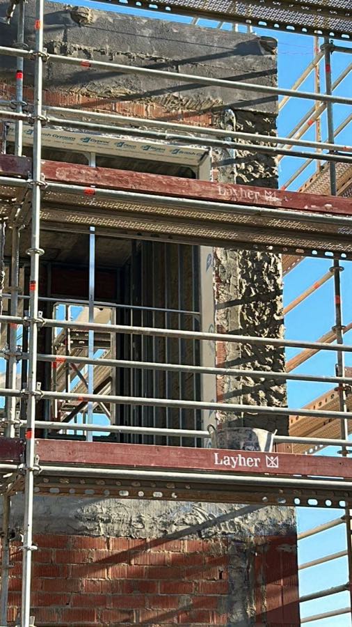 Operarios trabajando en la fachada de un edificio con andamio montado