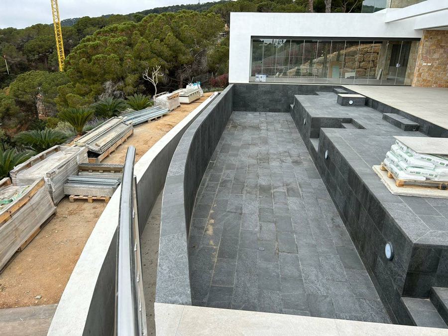 Vaso de piscina y terraza en construcción, con el pavimento de piedra colocándose